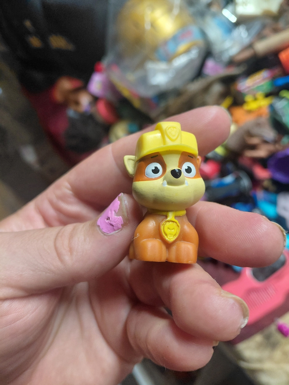 small plastic figurine of the character Rubble wearing a yellow construction har